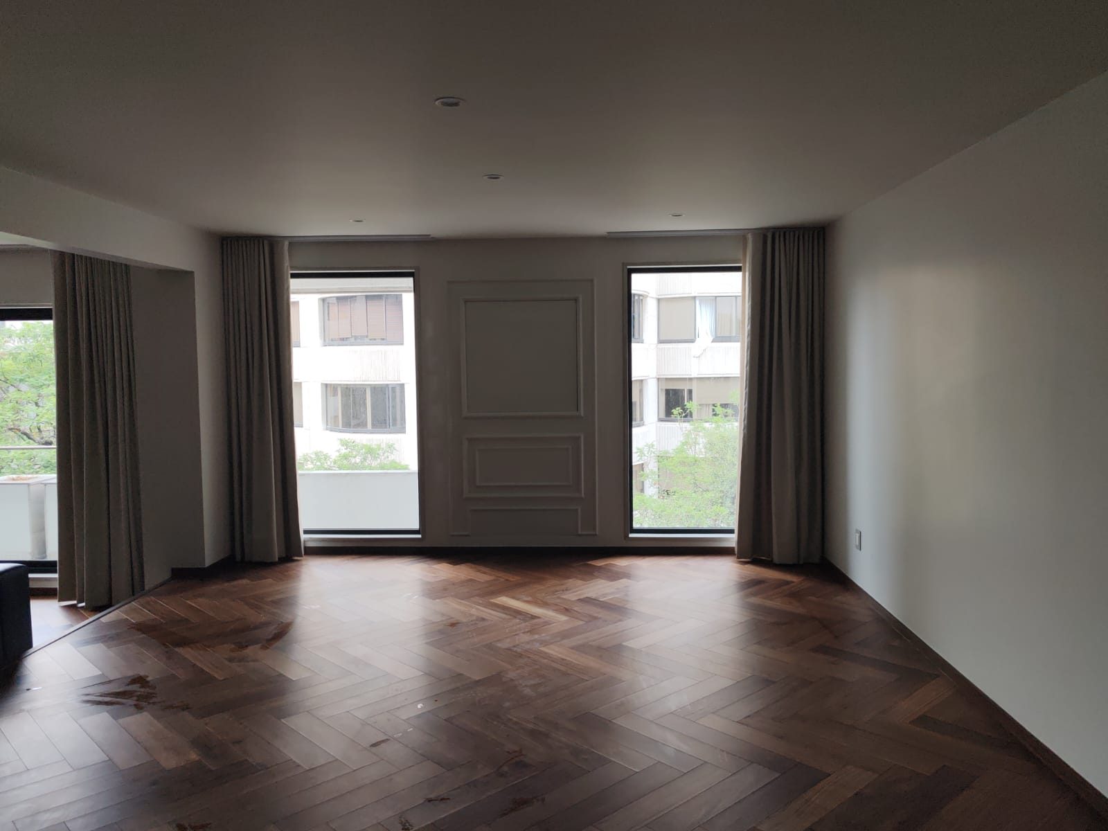 Sala amplia con cortinas a la medida, panel arquitectonico y piso de duela
