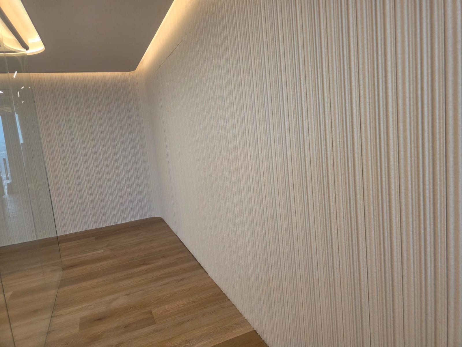 Muro curvo con papel tapiz texturizado e iluminacion LED indirecta